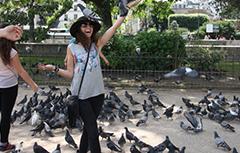 Girls smiling with a black hat on with pigeons all around her