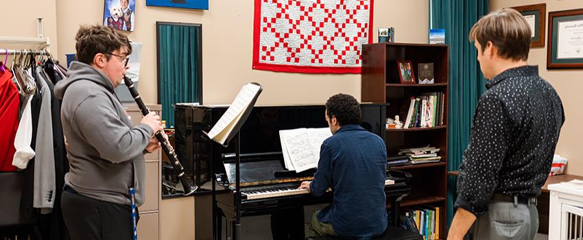 Student playing piano and student playing flute with instructor.