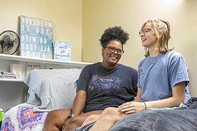 两个女学生坐在宿舍的床上笑