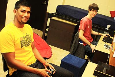 Two male students sitting in their dorm room playing video games