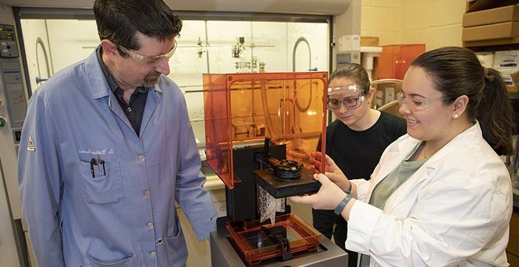 来自亨茨维尔的高年级化学学生麦迪逊·麦克布鲁姆(左)和来自佛罗里达州坎顿特的阿曼达·坦纳.，听医生说。. William Richert谈到了他们在3D打印领域对离子液体的研究. 