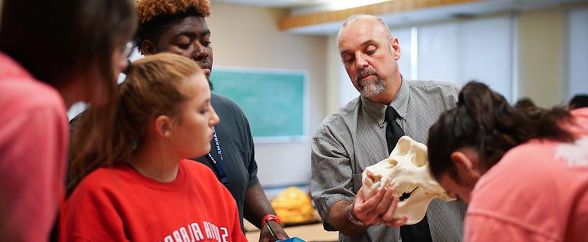 Dr. 卡尔在教室里拿着头骨向学生们展示.