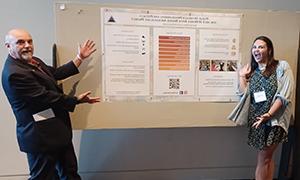 Professor 和 student pointing to research poster.